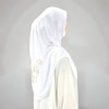 Hijab blanc avec broderies dorées porté sur un vêtement de couleur claire.