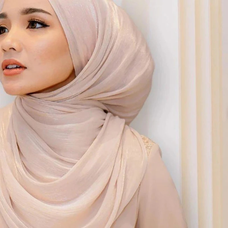 Primer plano de una mujer vistiendo un chal de hijab de gasa plisada y brillante color beige.