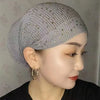Nahaufnahme einer Frau mit grauem elastischem Turbanhut, verziert mit kleinen Strasssteinen.