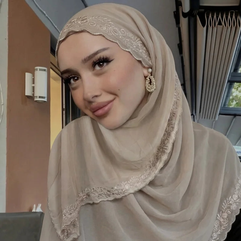 Une femme portant un foulard chiffon beige avec un bord de dentelle à cils.