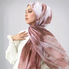 Eine Frau trägt einen Wasserfarben-drucken Stoff-Leinen-Hijab-Schal in Nuancen von staubigem Rosa und Beige.