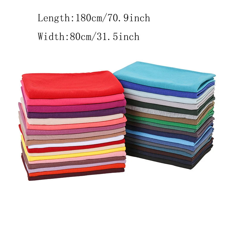 Ein Stapel gefalteter Baumwoll-Jersey-Schals in verschiedenen Farben, darunter rot, rosa, lila, grün und blau.