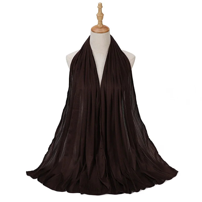 Pañuelo de jersey de algodón plisado marrón oscuro drapeado en el cuello de un maniquí.
