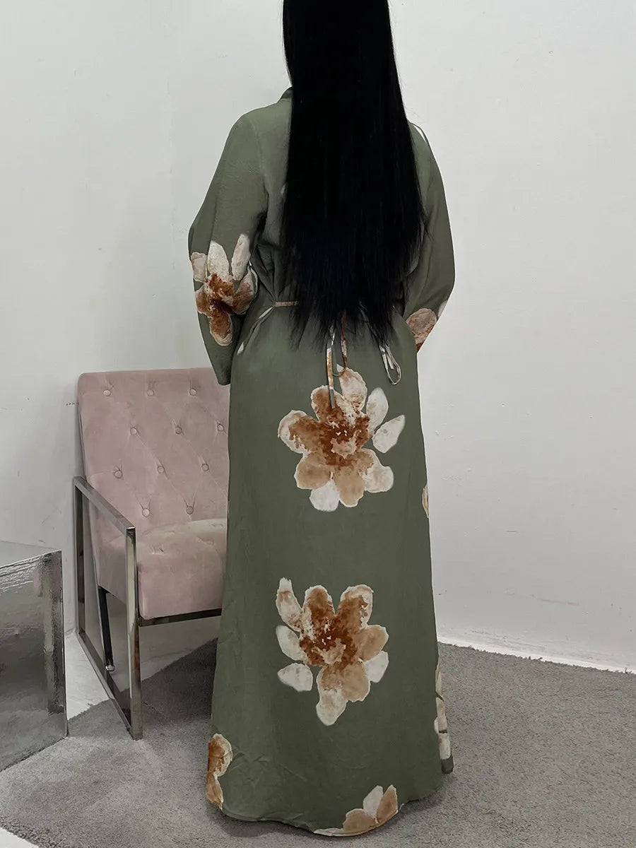 A full-length view of a moss green abaya kaftan dress with large floral print details.
