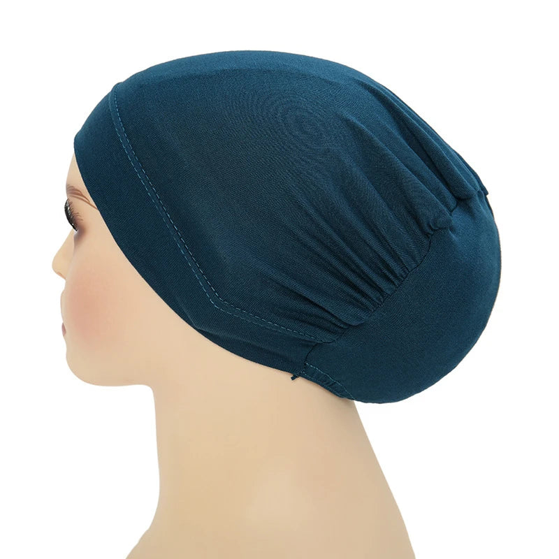 Un turbante instantáneo color verde azulado oscuro puesto en la cabeza de un maniquí.