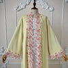 Une longue abaya jaune pâle avec des bordures de dentelle florale rose délicates sur le col avant.