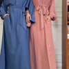 Zwei Frauen in langen Kaftan-Abayas, eine blau und eine rosa, stehen nebeneinander.