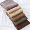 Pile de foulards hijab en rayon froncée dans diverses teintes neutres, beige, rose, vert olive et marron.