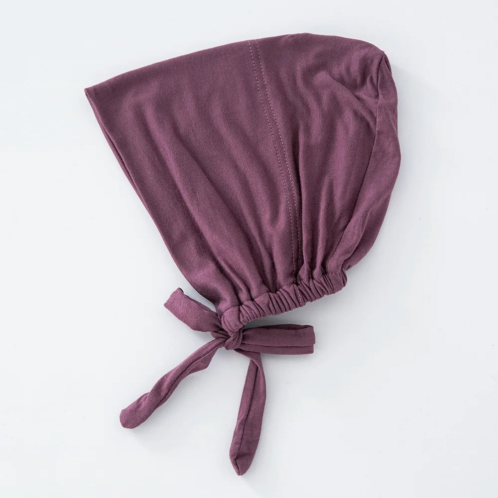 Tiefviolette Turban-Haube, gefaltet und unten gebunden.