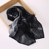 Un foulard voile imprimé noir et gris exposé sur un cadre en bois.