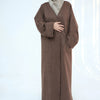 A woman wearing a brown abaya trench coat over a beige hijab.