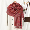 Chal vintage de bordado paisley rojo rosado drapeado sobre un abrigo crema.