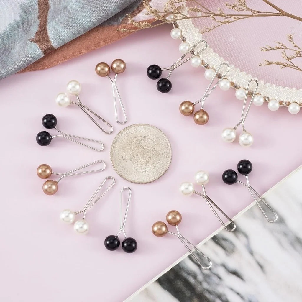 Un ensemble de douze épingles et pinces décoratives pour hijab dans des tons or, blanc perle et noir, présentées sur une surf