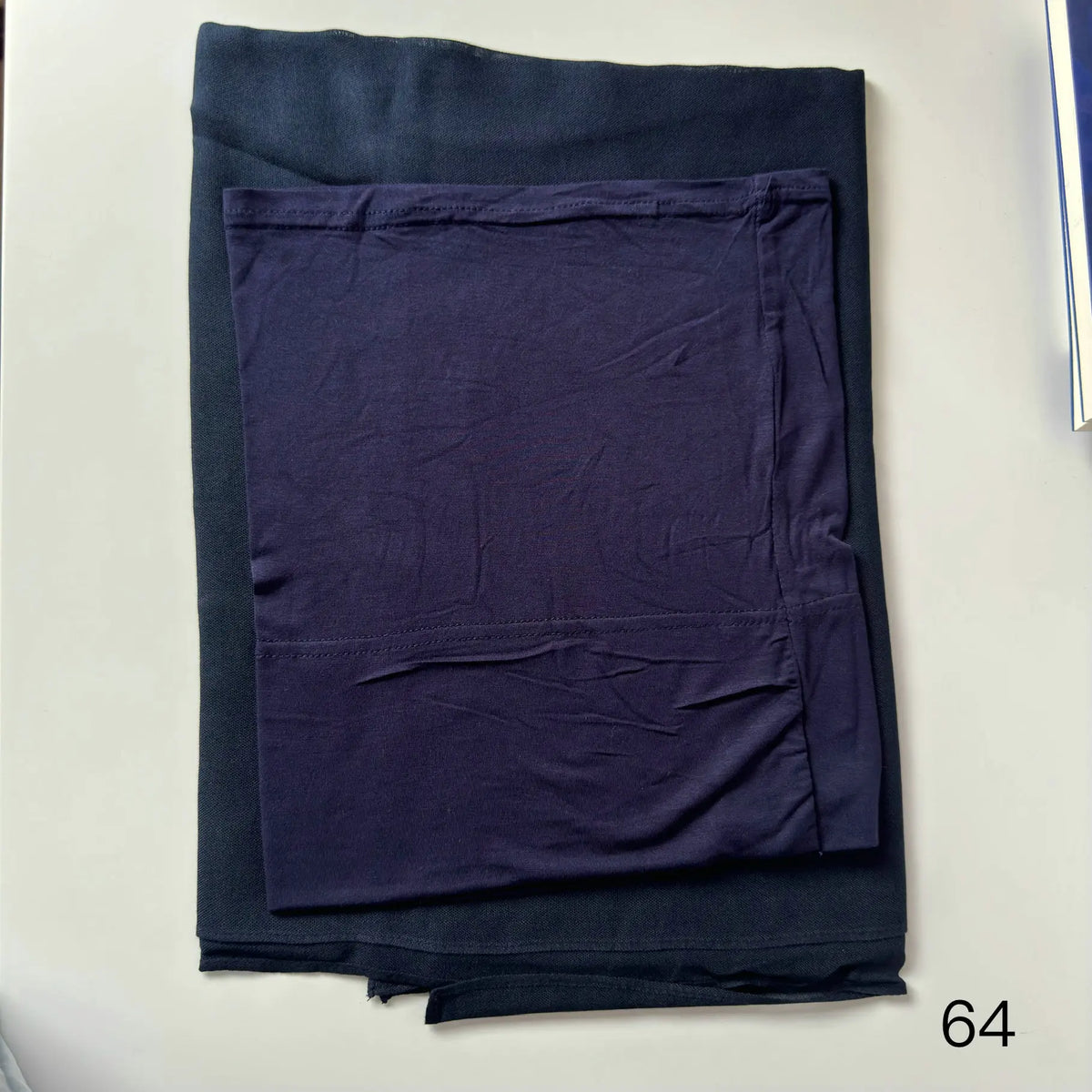 A dark navy blue soft modal rayon hijab set folded on a white surface.