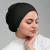 Una mujer vistiendo una gorra de hijab interior de jersey negro, mirando pensativamente hacia abajo.
