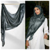 Eine Frau trägt einen grauen Aquarell-Ombré-gedruckten Rayon-Modal-Hijabschal und ein weißes Kleid.