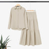 Beige, elegantes, schlichtes Hemd und mehrlagiges Rock-Set auf einem Bügel.
