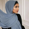 Una mujer vistiendo un pañuelo de chifón hijab azul claro, mirando hacia un lado.