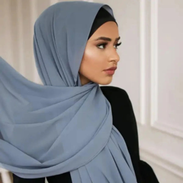 A woman wearing a light blue chiffon hijab scarf, looking to the side.