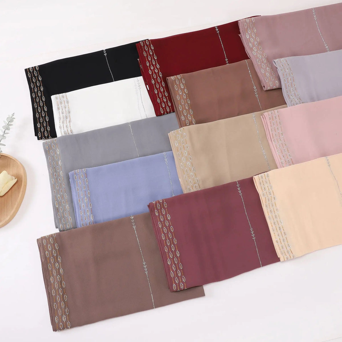 Colección de pañuelos de chifón y pedrería doblados en tonos rosa, malva, beige y púrpura.