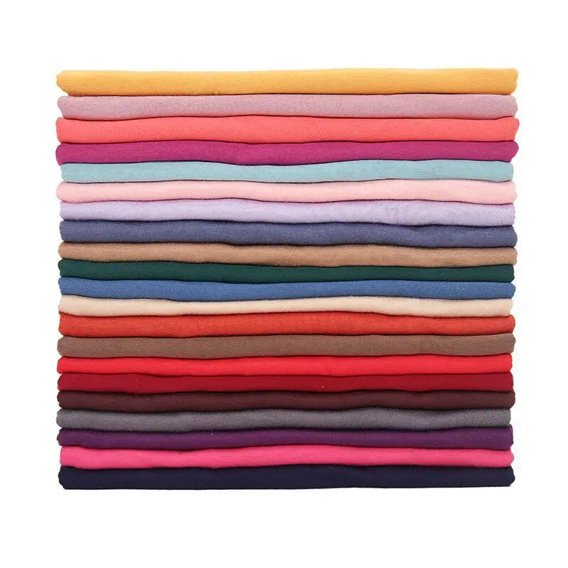 Una pila de pañuelos de hijab de algodón modal premium doblados en varios tonos de rosa, púrpura, azul y gris.