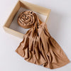 A tan ribbed jersey hijab scarf is draped over a light wooden frame.