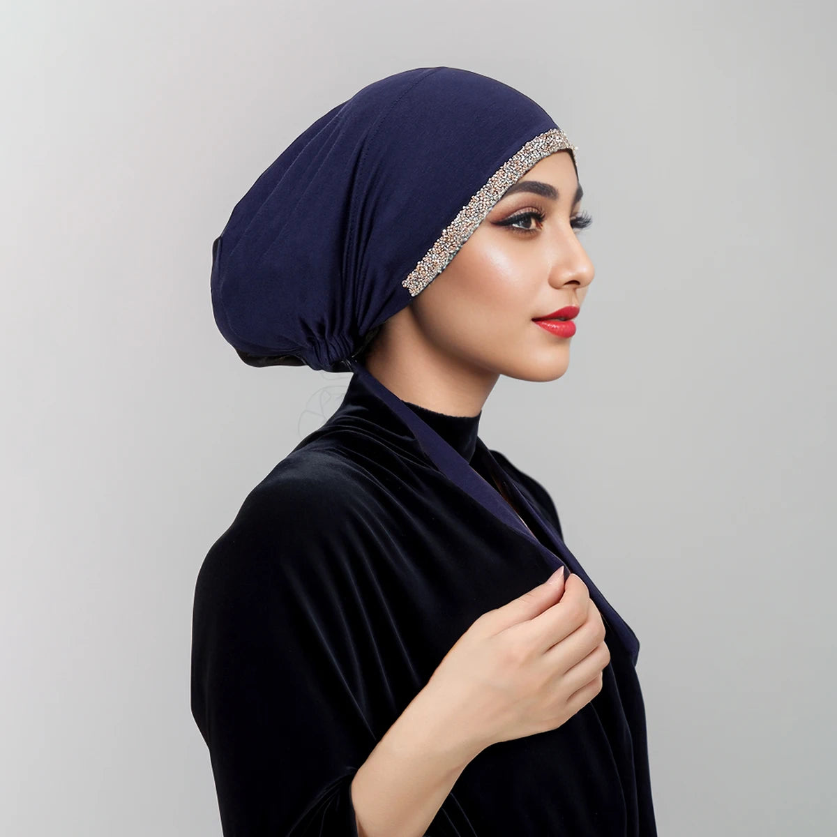 Eine Frau trägt einen dunkelblauen Samt-Hijab mit funkelnder Strassverzierung und einem passenden Oberteil.
