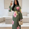 Eine Frau präsentiert ein elegantes Sommer-Blumen-Abaya-Kleid in Olivgrün mit rosa und gelben Blumenmustern.
