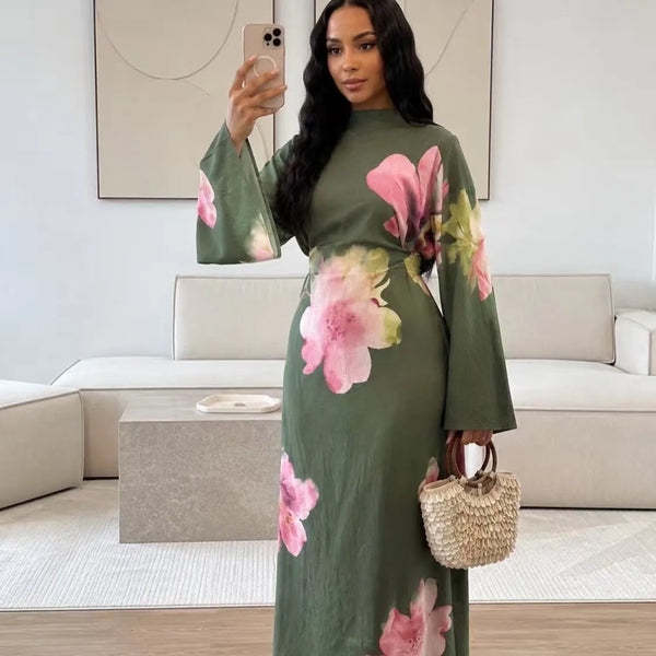 A woman models an elegant summer floral abaya dress in olive green with pink and yellow floral patterns.