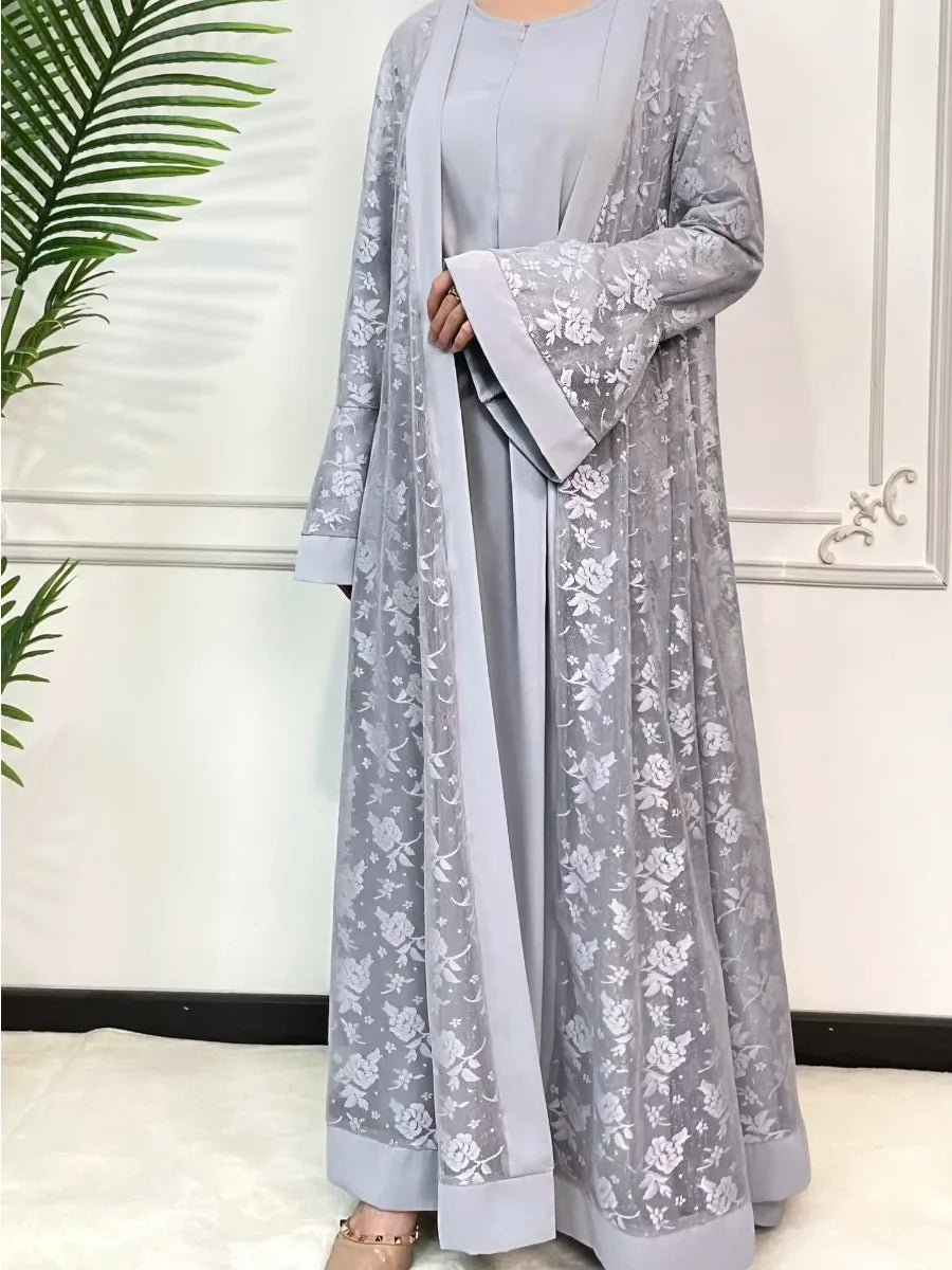 Une longue tenue abaya en dentelle gris clair pour femmes avec broderie florale et un vêtement intérieur assorti.