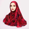 Eine Frau trägt einen roten, aquarellartigen Blumenmuster-Hijabschal über einem Mannequin.
