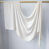 Foulard modal uni blanc drapé sur une tige dorée sur fond clair.
