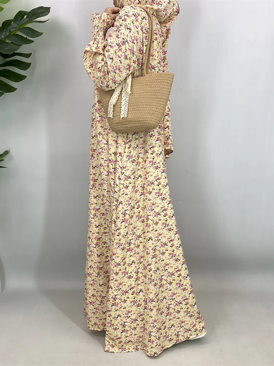 Una mujer vistiendo una elegante caftán de abaya floral y llevando un bolso tejido beige.