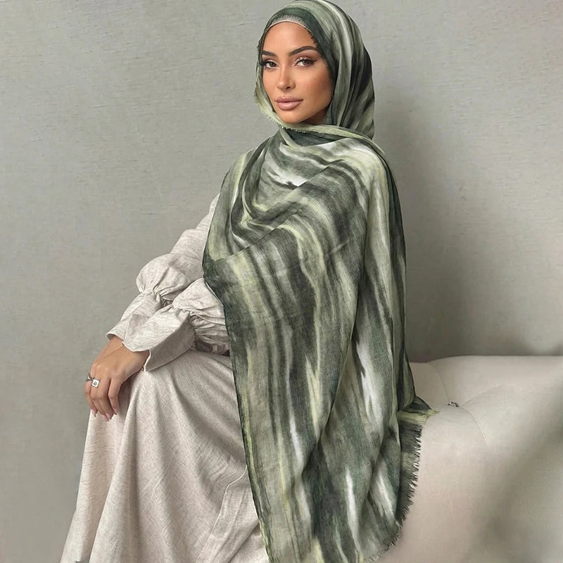 Una mujer vistiendo un pañuelo de hijab a rayas acuareladas verde y gris con un vestido de color claro.