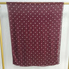 Ein tiefburgunder, durchscheinender Schal mit kleinen weißen Polka Dots vor hellem Hintergrund.