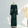 Una abaya de color verde esmeralda oscuro, de largo, mostrada en maniquí.