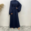 Una elegante abaya de encaje azul marino para mujeres se muestra contra una pared blanca.