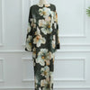 Schwarze Abaya mit großem Blumenmuster in blassem Pfirsich und Salbeigrün auf einem Mannequin.