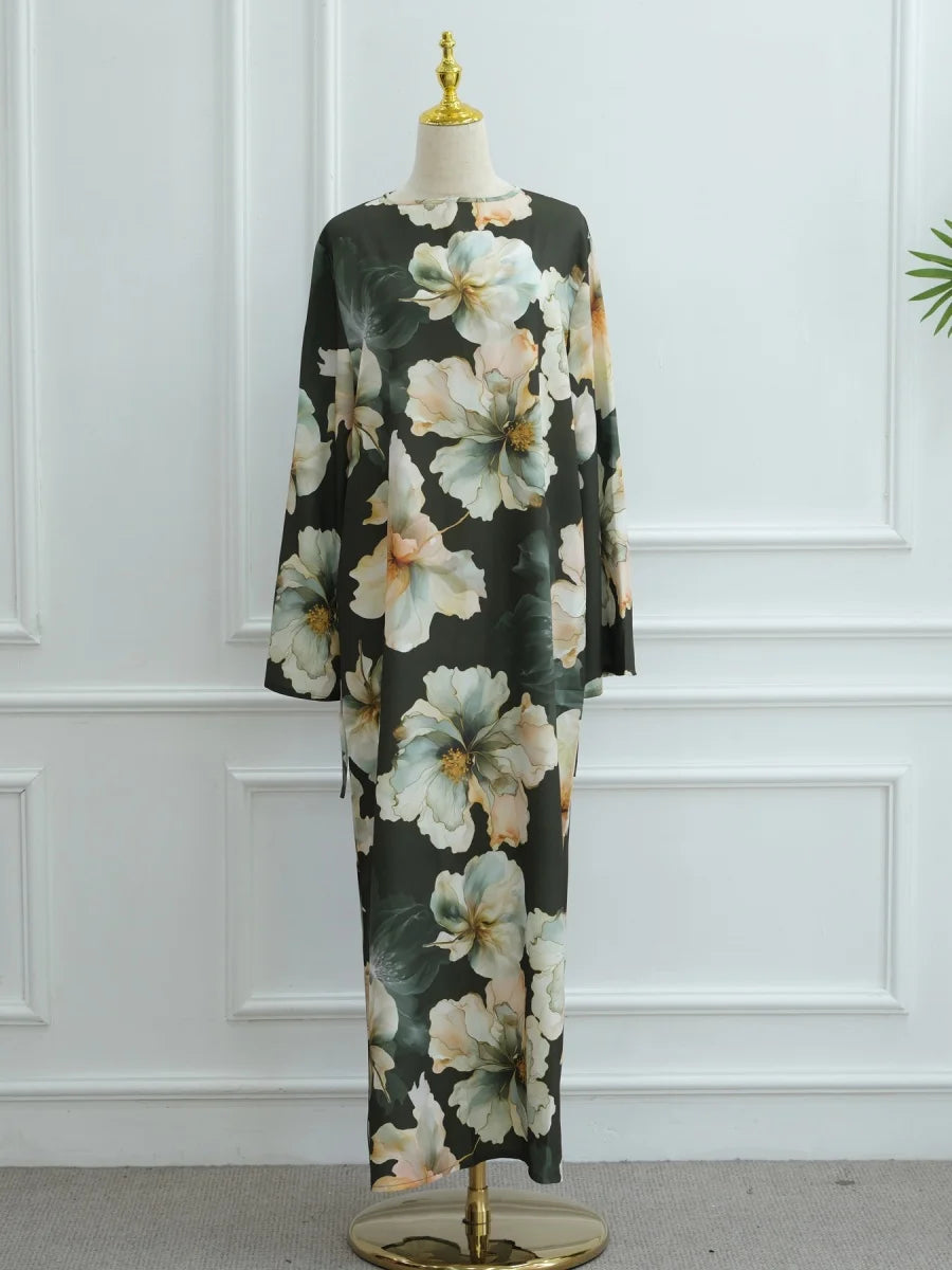 Schwarze Abaya mit großem Blumenmuster in blassem Pfirsich und Salbeigrün auf einem Mannequin.