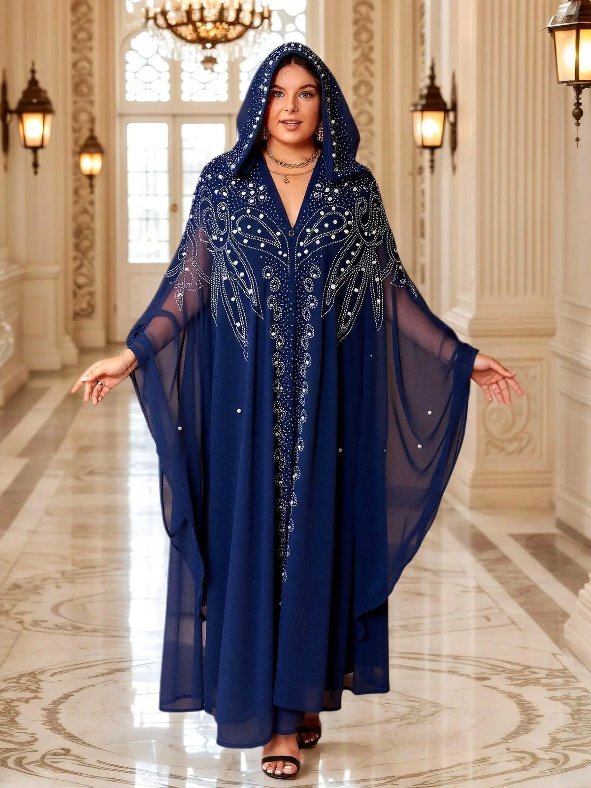Una mujer modela un largo y fluido vestido maxi abaya azul marino con mangas de murciélago en un elegante entorno interior.