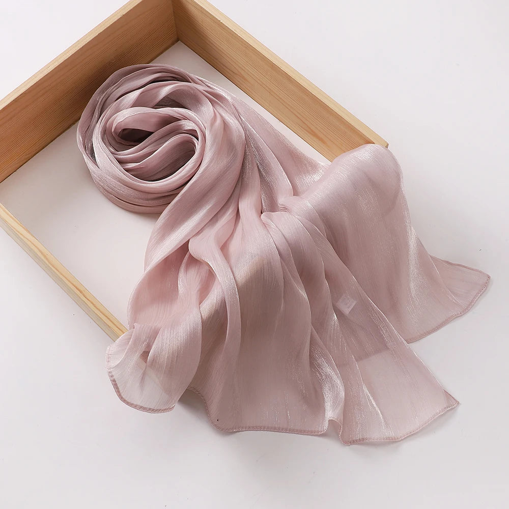Un châle en mousseline crinklée rose pâle drapé dans un cadre en bois.