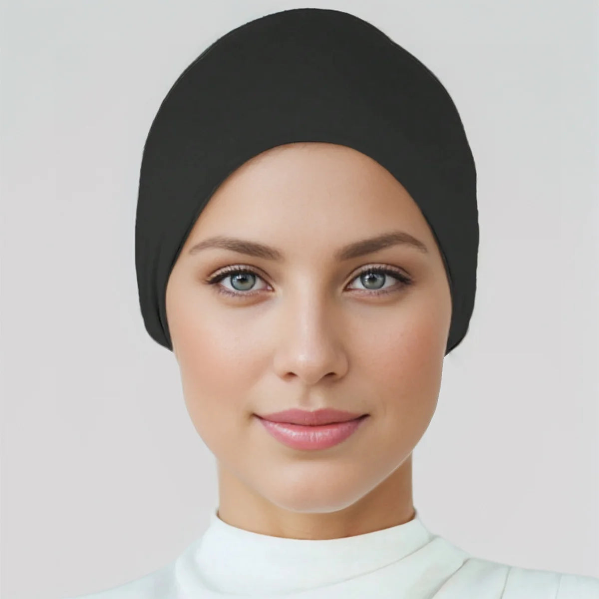 Eine Frau trägt eine schwarze weiche Baumwoll-Stretch-Hijab-Kappe und ein Stirnband.