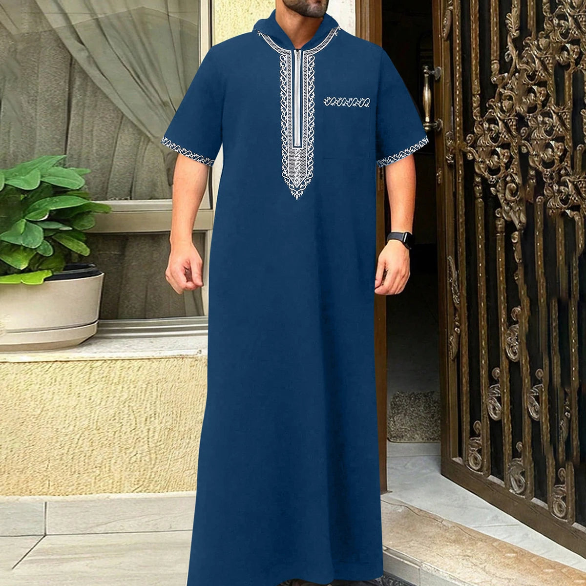 A man wearing a navy blue Moroccan ethnic thobe with a stand collar and silver embroidery.