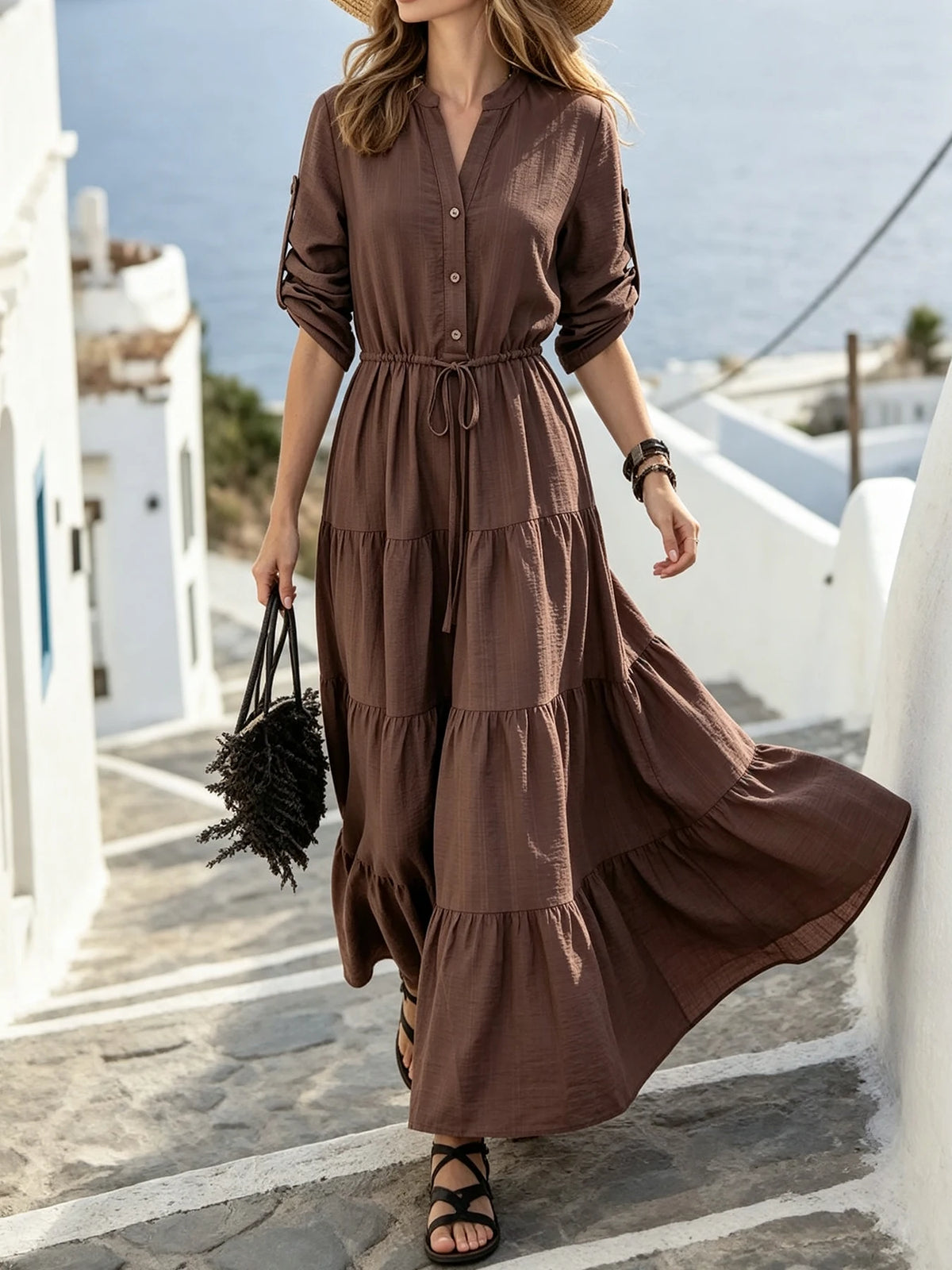 Eine Frau in einem braunen Maxi-Kleid mit Kordelzug und Rüschensaum geht nach draußen.