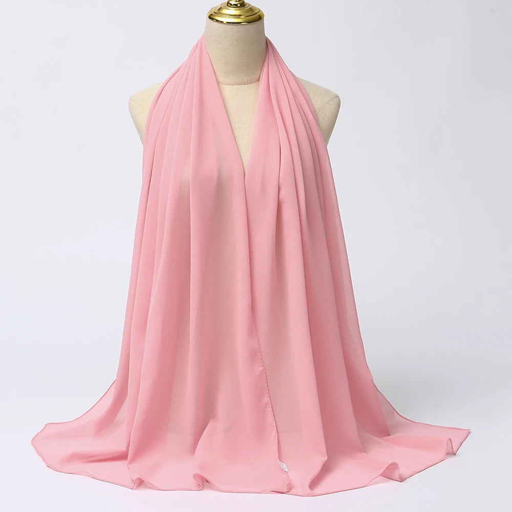 Ein rosa Chiffon-Hijab-Schal über dem Hals und den Schultern einer Mannequin drapiert.