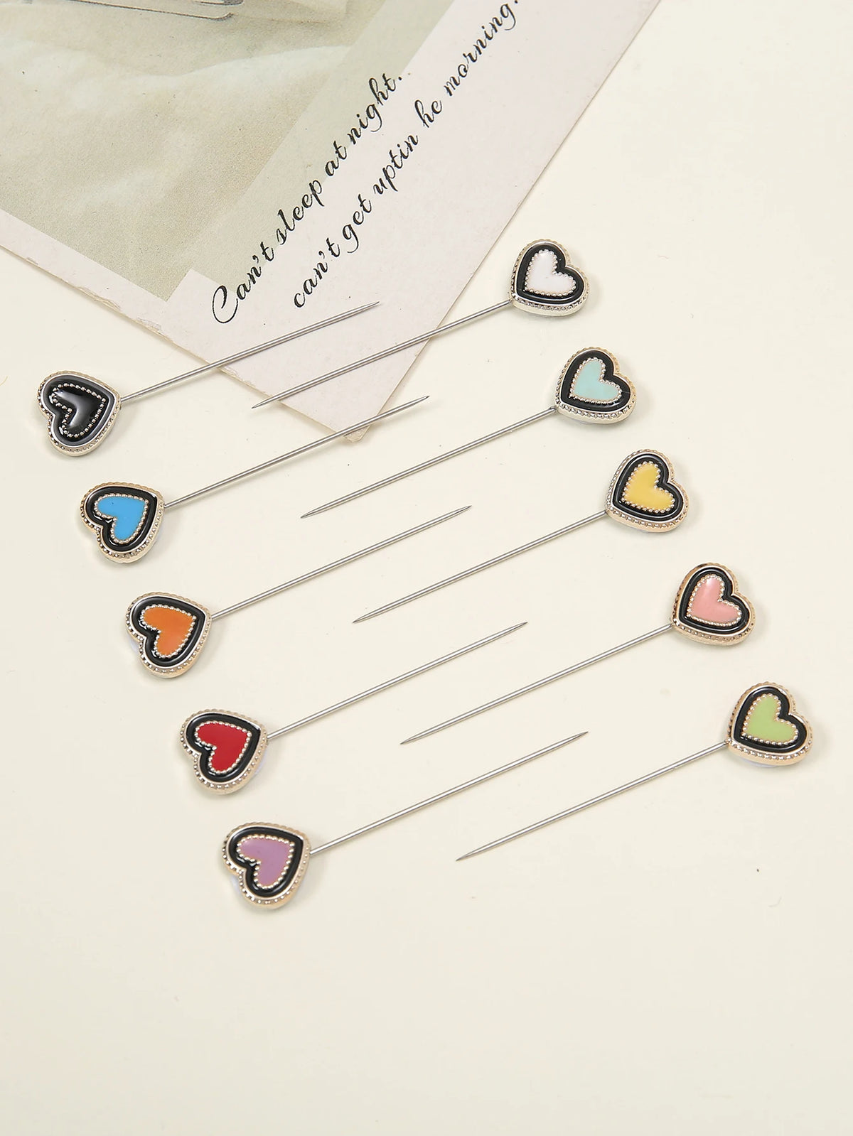 Un juego de pines para hijab de seda con diversos diseños de mariposas en forma de corazón y colores pastel.