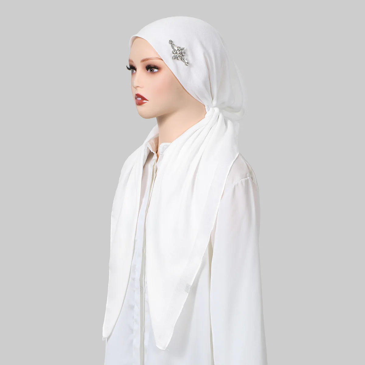 Una mujer vistiendo un gorro de hijab de lino blanco y una blusa a juego con bordado plateado.
