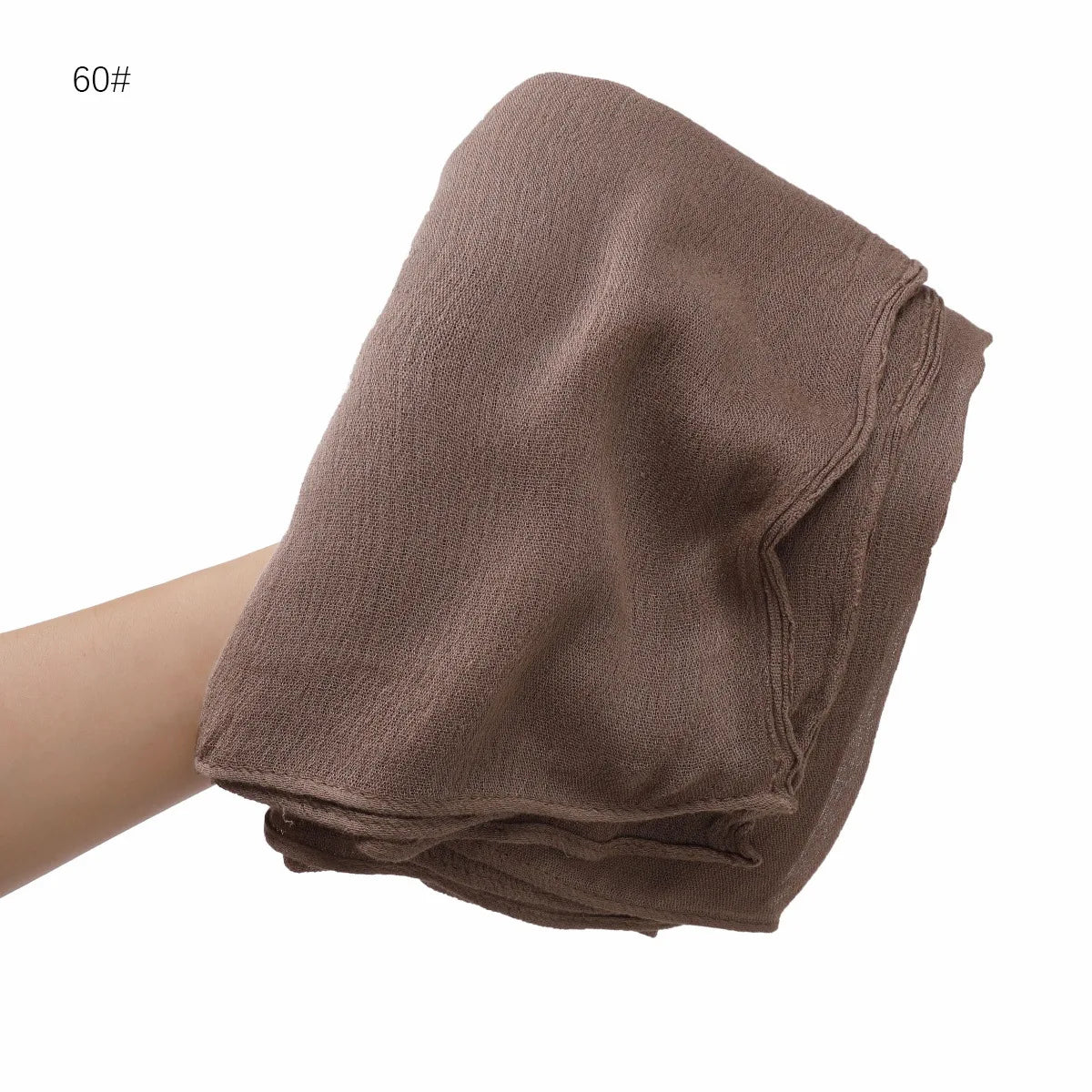 Écharpe châle en crêpe de rayon marron pliée et présentée dans la main.