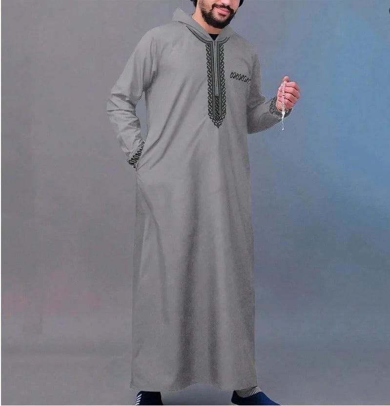 Un homme portant une longue robe musulmane grise avec de la broderie verticale sur la poitrine.