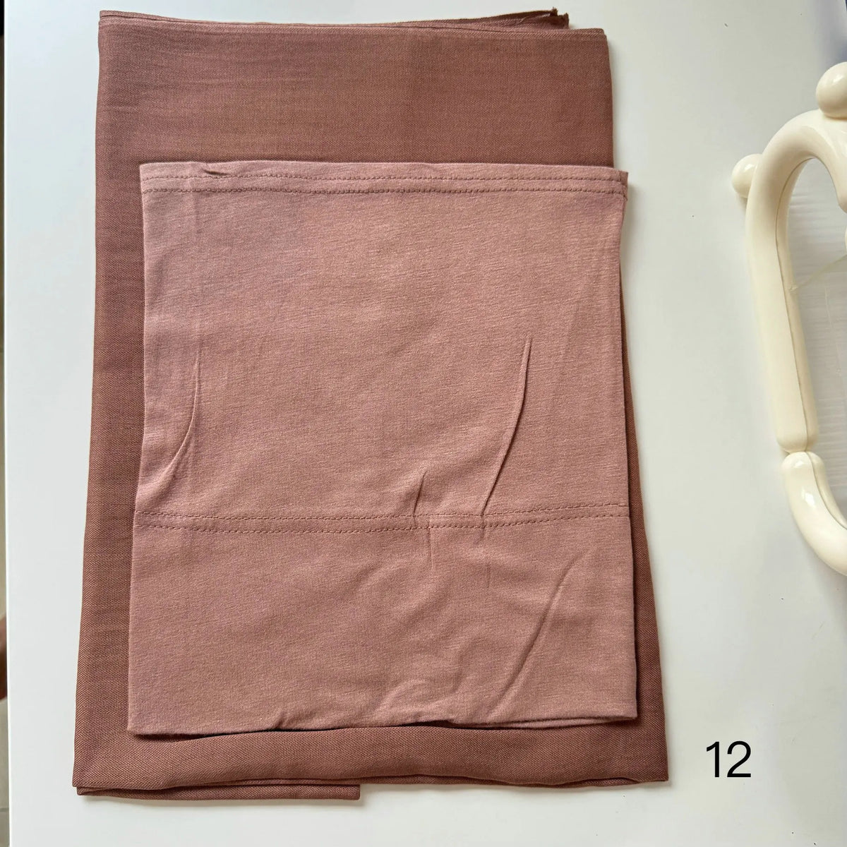 A folded dusty rose soft modal rayon hijab set for women displayed on a white surface.